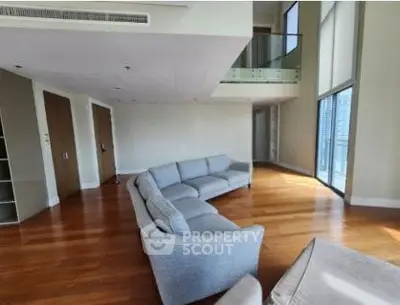 Spacious modern living room with hardwood floors and large windows in luxury apartment.