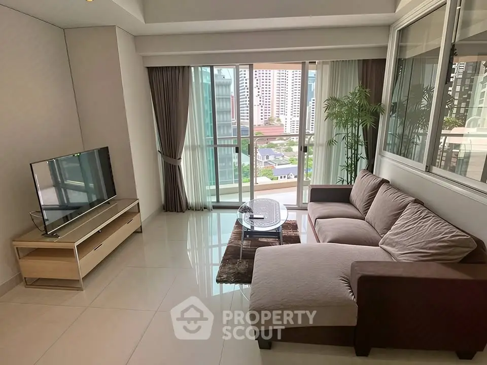 Spacious living room with modern decor and large windows offering city views.