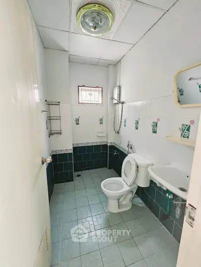Compact bathroom with tiled walls and floor, featuring a toilet and shower area.