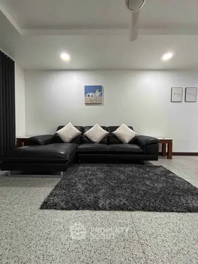 Modern living room with sleek black leather sofa and minimalist decor