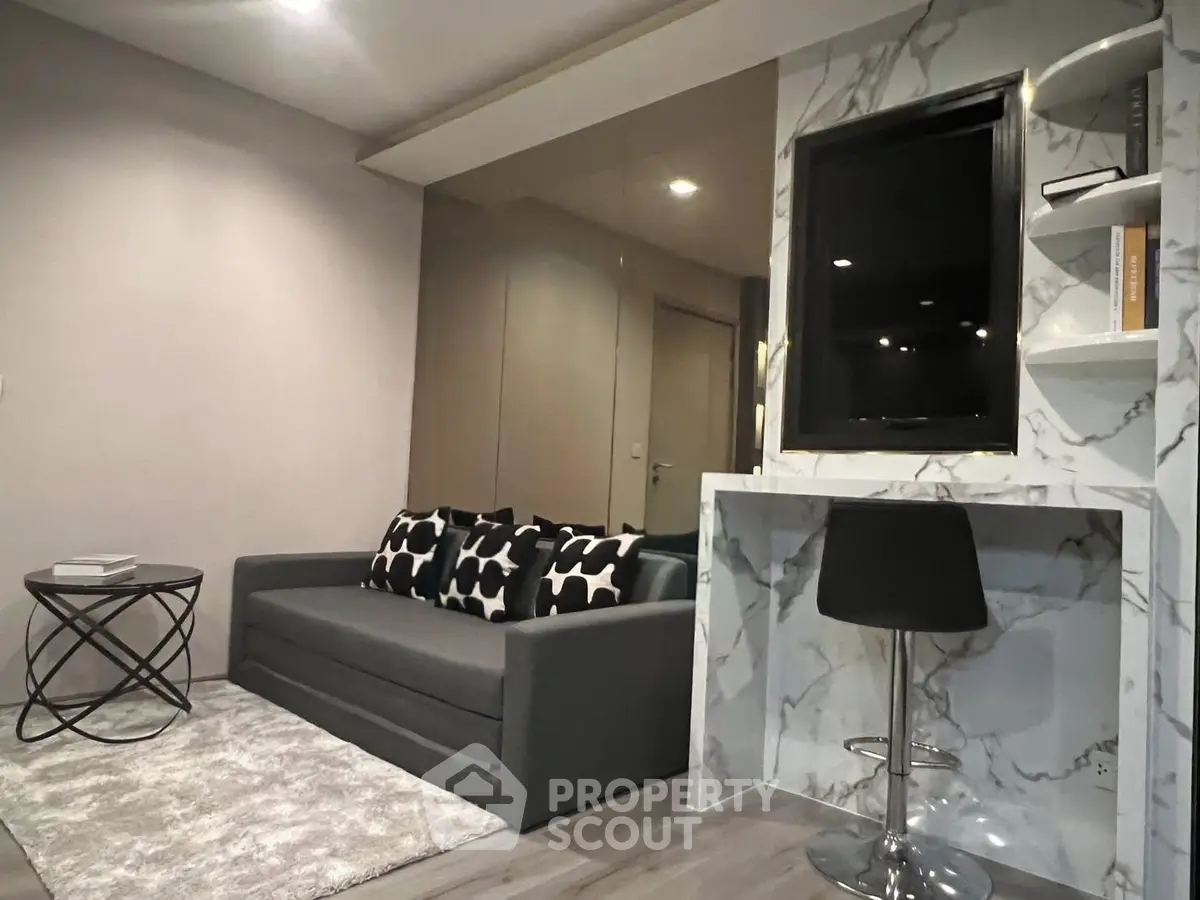 Modern living room with stylish sofa, marble accent wall, and sleek decor.