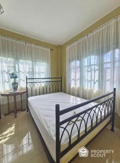 Bright and airy bedroom with large windows and elegant metal bed frame