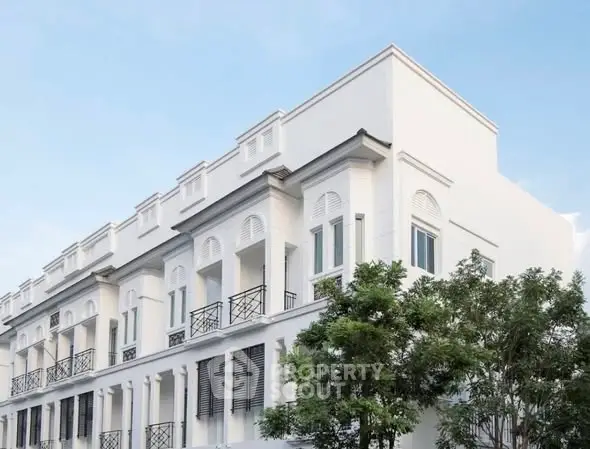 Elegant white townhouse exterior with classic architectural design and lush greenery.