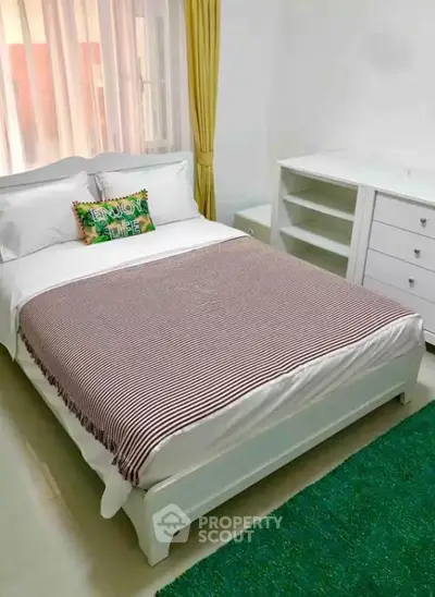 Cozy bedroom with white furniture and colorful accents, perfect for relaxation.