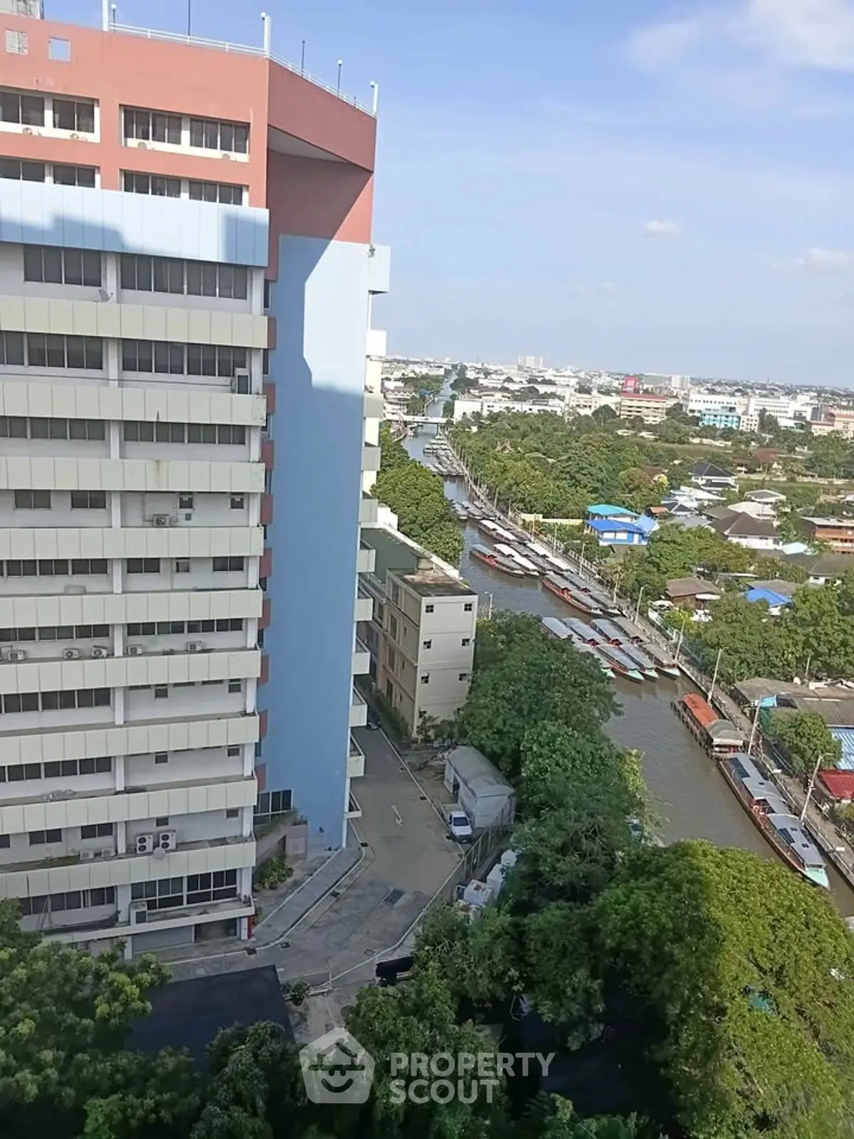 Stunning cityscape view from high-rise building overlooking a serene canal and lush greenery.