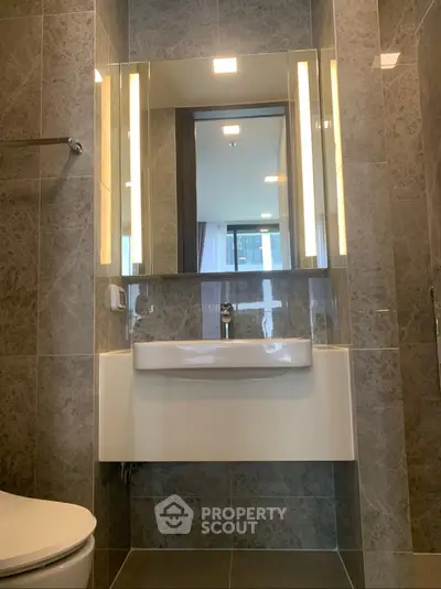 Modern bathroom with sleek sink and illuminated mirror in a stylish apartment.