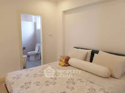 Cozy bedroom with plush bedding and ensuite bathroom in modern apartment