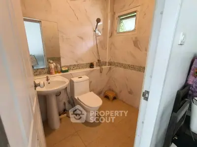 Modern bathroom with sleek fixtures and marble walls, featuring a shower and compact design.