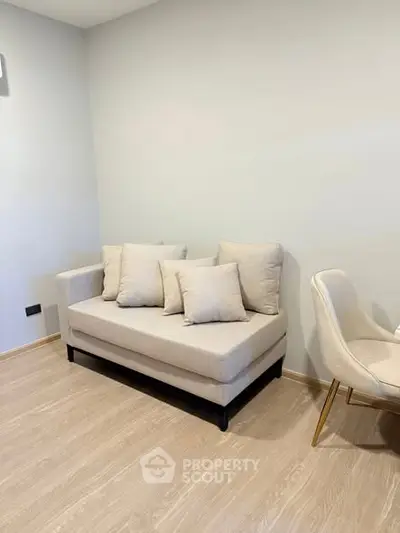 Modern minimalist living room with cozy beige sofa and elegant chair on wooden flooring.