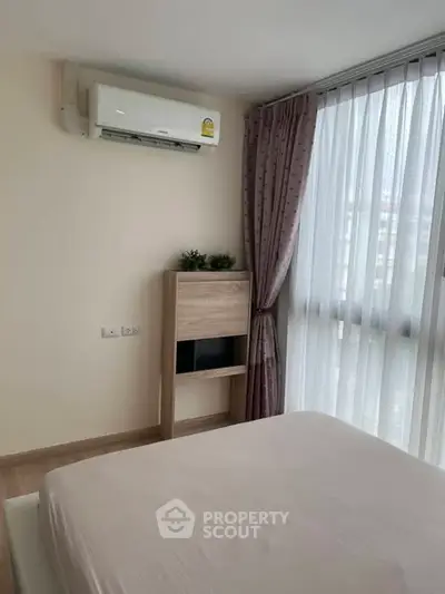 Cozy bedroom with air conditioning and large window for natural light