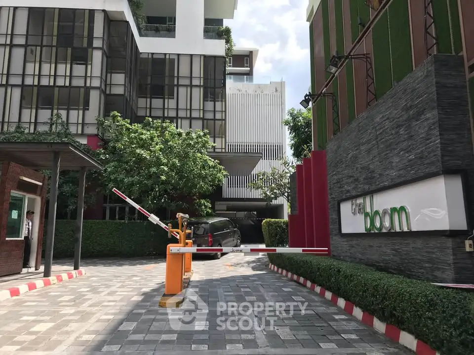 Modern building entrance with security barrier and lush greenery.