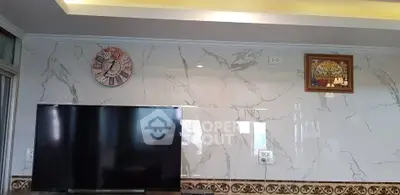 Modern living room with marble wall, large TV, and stylish clock