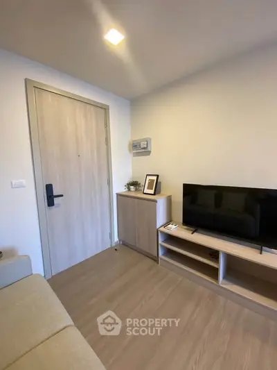 Modern living room with sleek wooden furniture and flat-screen TV, showcasing minimalist design.