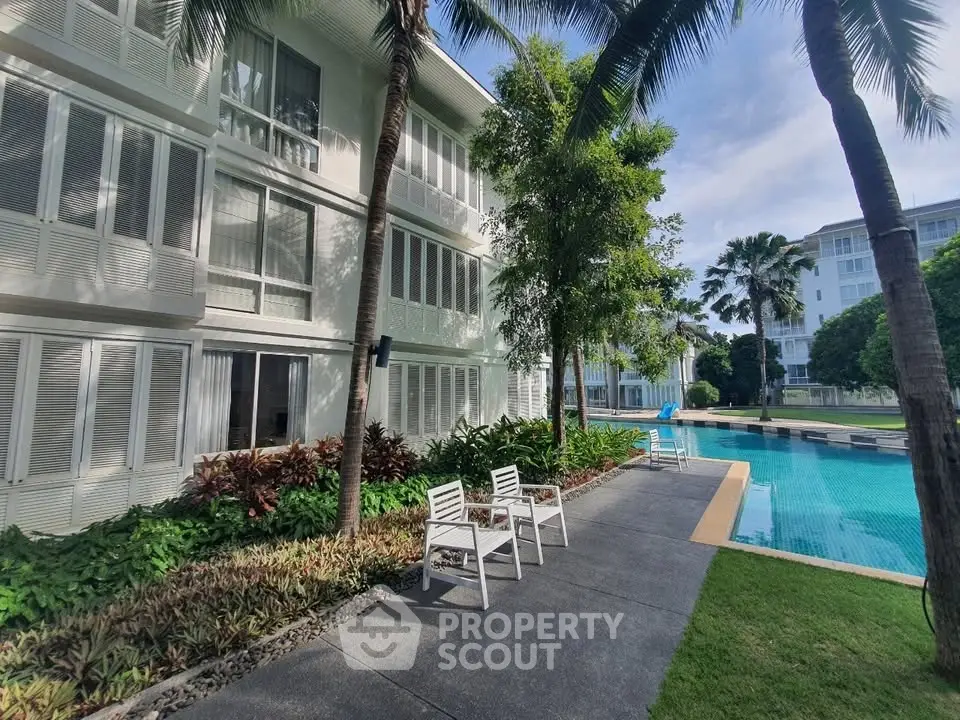 Luxurious apartment complex with poolside seating and lush greenery