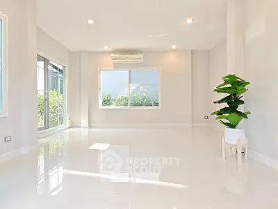 Spacious sunlit living room with glossy tiles and large windows, perfect for modern living.