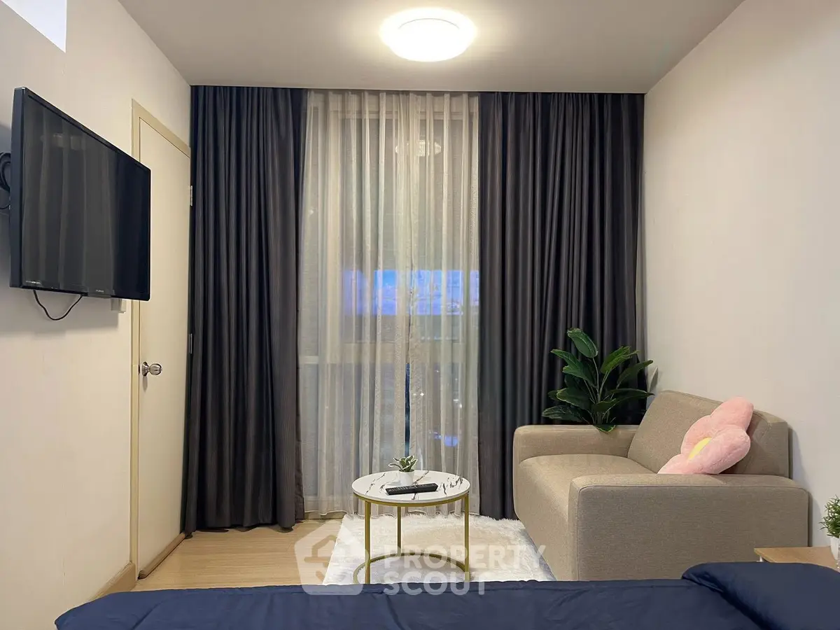 Cozy living room with modern decor and natural light, featuring a comfortable sofa and wall-mounted TV.