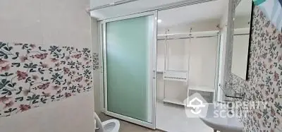 Spacious bathroom with floral tiles and sliding glass door