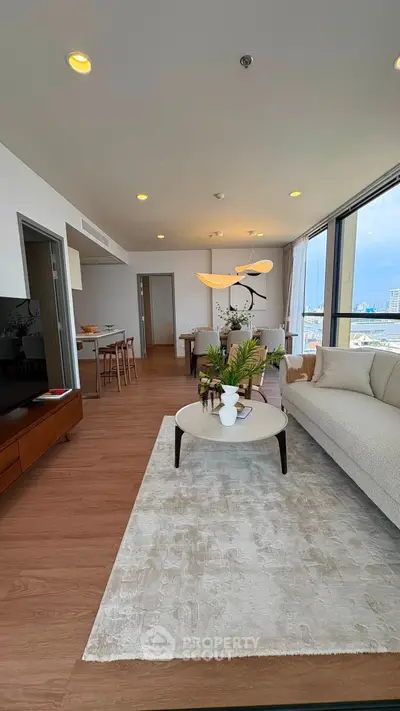 Spacious modern living room with elegant decor and large windows offering city views.