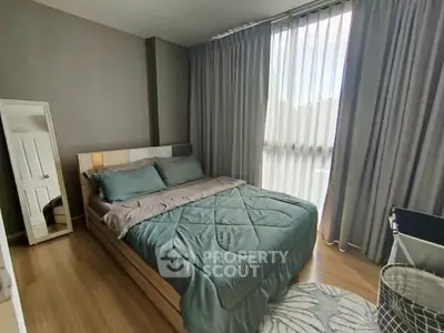 Cozy bedroom with modern decor and natural light through large window.