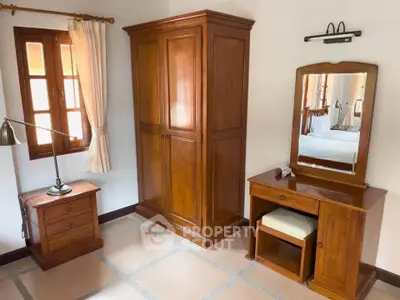 Charming bedroom with wooden furniture and natural light, perfect for cozy living.