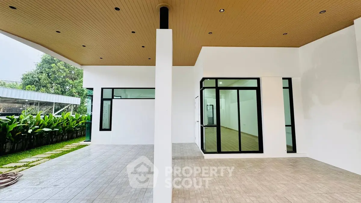 Modern minimalist home exterior with spacious patio and lush garden view.
