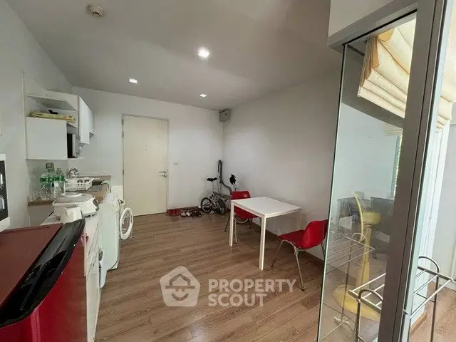 Modern apartment interior with open kitchen and dining area, featuring sleek appliances and wooden flooring.