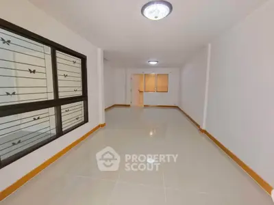 Spacious empty room with tiled flooring and large window, perfect for customization.
