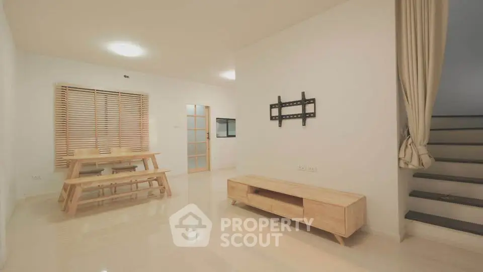 Spacious minimalist living room with wooden furniture and staircase