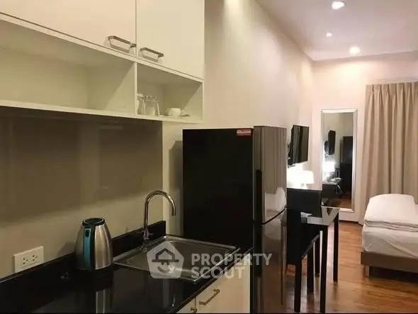 Modern studio apartment with sleek kitchen and cozy sleeping area, perfect for urban living.