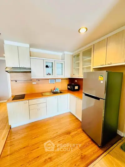 Modern kitchen with sleek cabinetry and stainless steel fridge in a bright apartment.