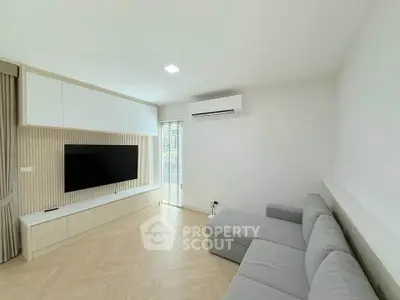 Modern living room with sleek design, featuring a large TV and comfortable gray sofa.