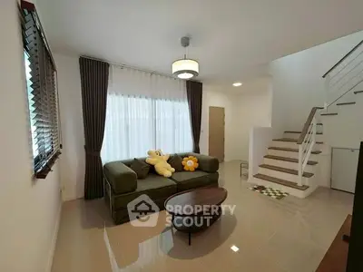 Cozy living room with plush sofa and modern staircase in a bright, airy space.