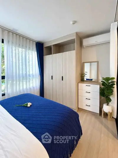 Modern bedroom with blue accents, large window, and stylish storage solutions.