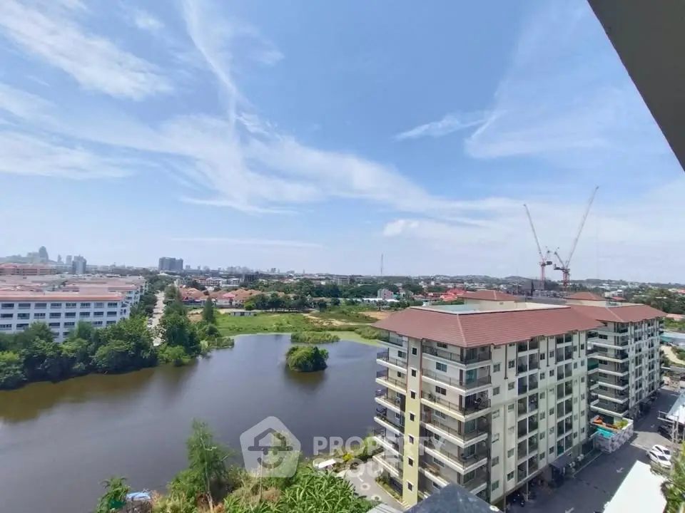 Stunning aerial view of modern apartment complex with serene lake and cityscape backdrop.