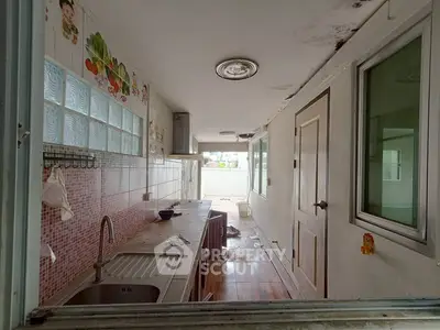 Compact kitchen with tiled backsplash and stainless steel sink in a narrow layout.