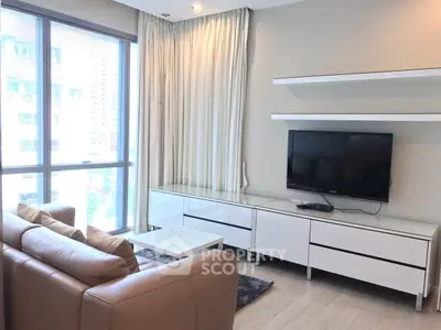 Modern living room with large windows, sleek furniture, and a wall-mounted TV in a high-rise apartment.