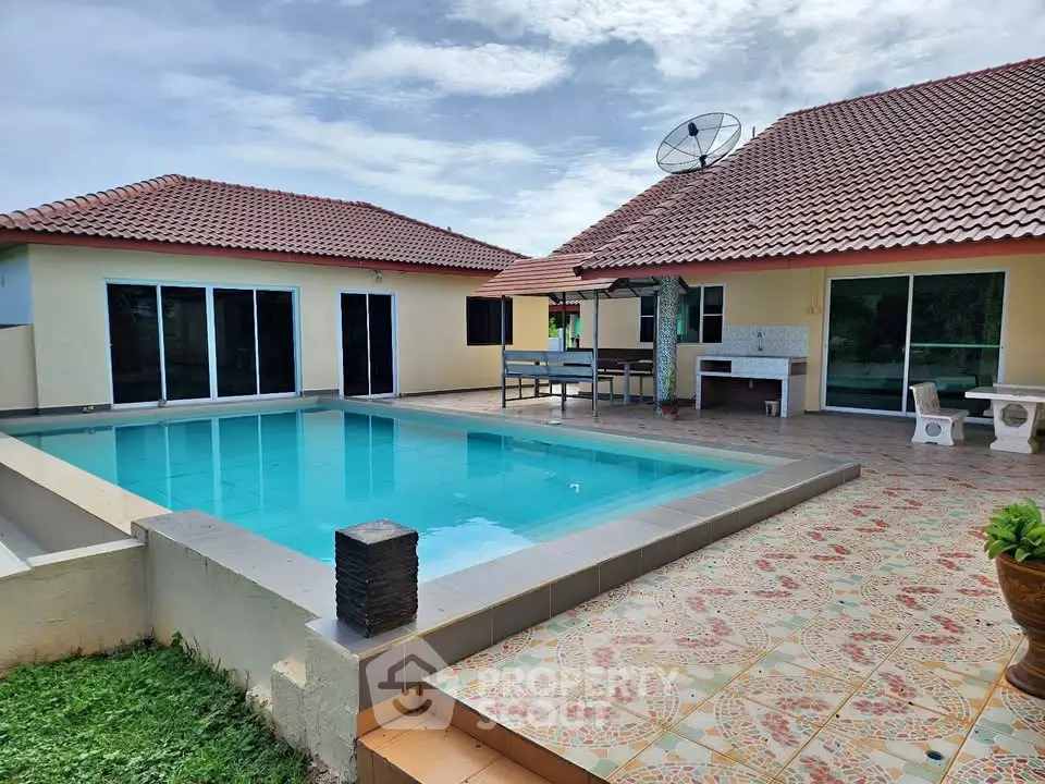 Spacious villa with private pool and tiled patio under a clear sky.