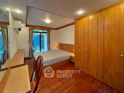 Spacious bedroom with wooden flooring and built-in wardrobe, featuring a large window for natural light.