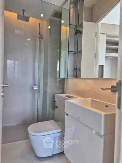 Modern bathroom with sleek fixtures and glass shower enclosure in a contemporary apartment.