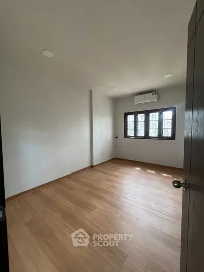 Spacious empty room with wooden flooring and natural light, ideal for customization.