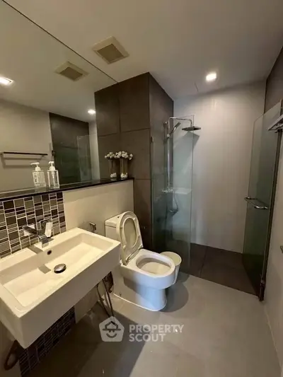 Modern bathroom with sleek design, featuring a glass shower and stylish sink.