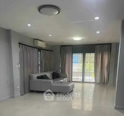 Spacious modern living room with sleek gray sofa and large windows for natural light.