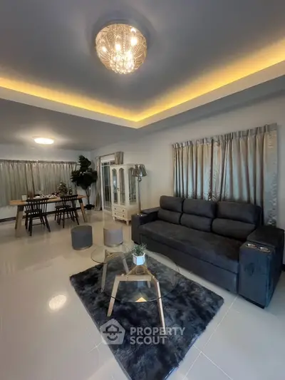 Spacious modern living room with elegant decor and dining area, featuring plush seating and ambient lighting.