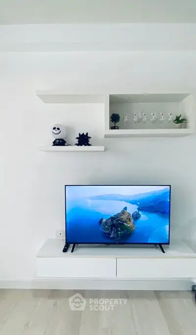 Modern living room with sleek TV setup and minimalist decor shelves.