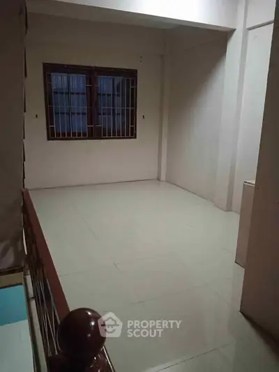 Spacious unfurnished room with tiled flooring and barred window, ideal for customization.