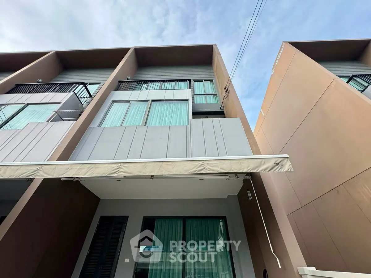 Modern townhouse exterior with large windows and balcony, showcasing contemporary architectural design.