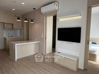 Modern open-plan living room with kitchen island and wall-mounted TV in stylish apartment