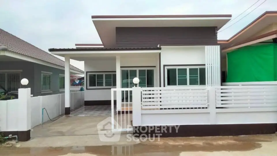 Modern single-story house with sleek design and spacious driveway in a suburban neighborhood.