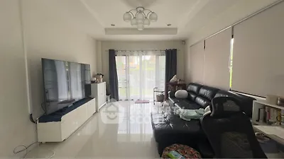 Spacious living room with modern decor and large TV, perfect for relaxation.