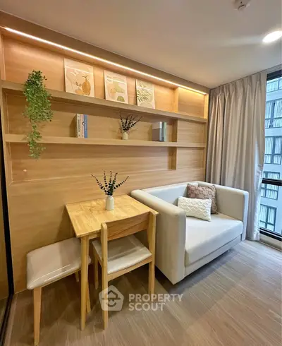 Cozy living room with modern decor and natural light, featuring a compact dining area and stylish shelving.